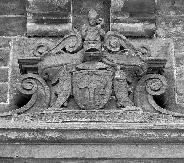 Glasgow's Coat of Arms, carved stone featuring figure of St. Mungo, carved leafs, carved fish, and the motto 'Let Glasgow Flourish'